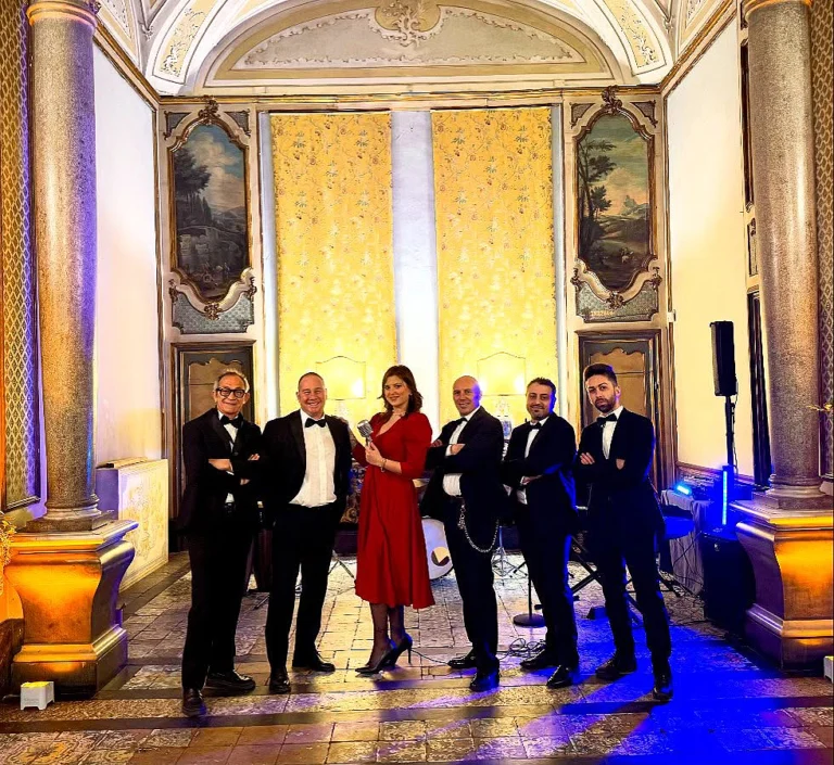 La nostra band di musica ed eventi live in un'elegante location storica, pronta ad esibirsi in una serata esclusiva. Sei musicisti professionisti, vestiti in abito da cerimonia, uniti dalla passione per la musica dal vivo di qualità. Un ensemble ideale per matrimoni di prestigio, eventi aziendali di classe e cerimonie raffinate. L’atmosfera suggestiva, arricchita da dettagli architettonici unici, esalta il carattere sofisticato delle nostre performance di musica ed eventi live, pensate per regalare emozioni autentiche e momenti indimenticabili.